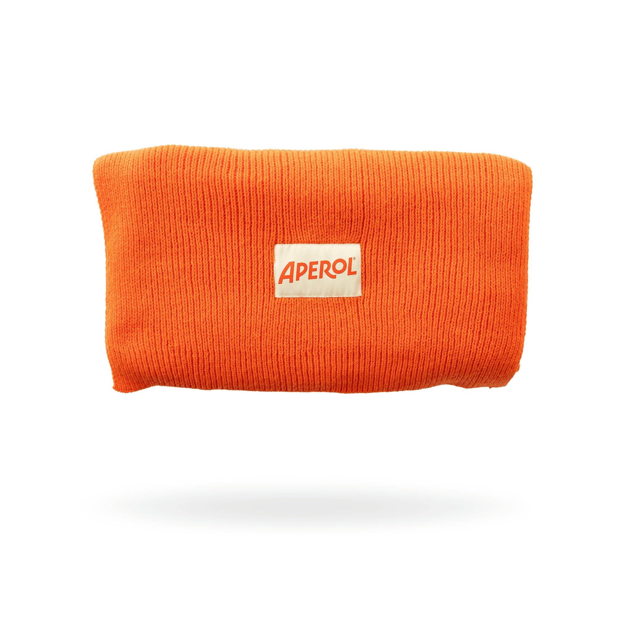 Bright orange Aperol-branded knit scarf with a cream-colored rectangular patch featuring the Aperol logo in red.